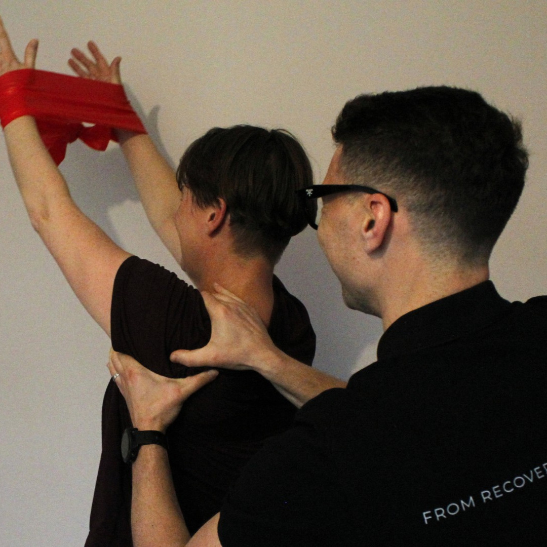 Physiotherapist assisting patient with shoulder rehabilitation exercises using resistance band